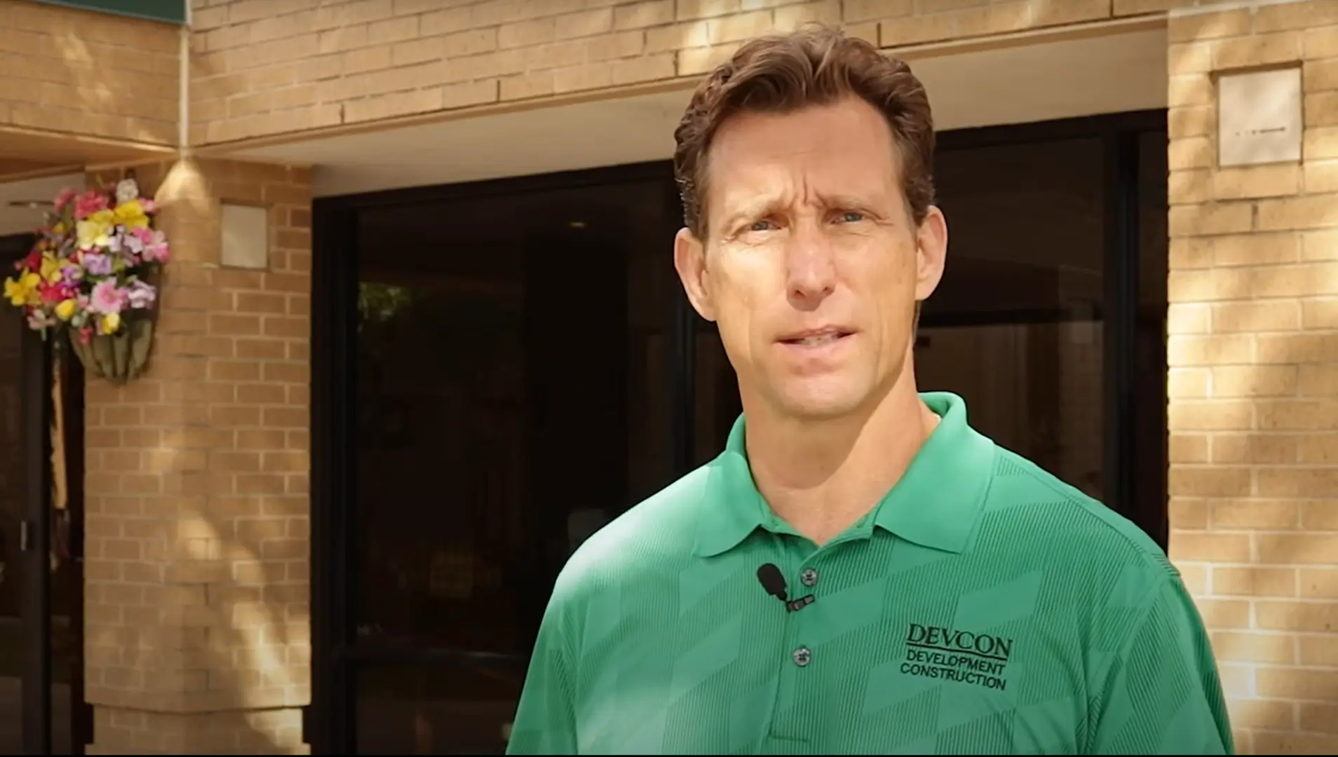 Man in green polo shirt standing outside a building.